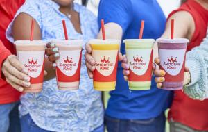 People hold out smoothies from Smoothie King in various colors and flavors.