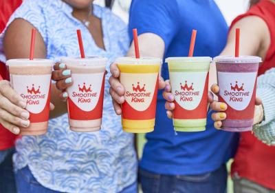 People hold out smoothies from Smoothie King in various colors and flavors.