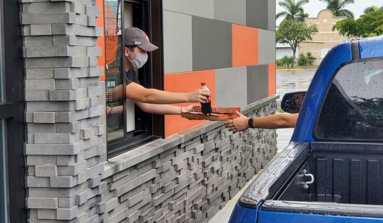 Blaze Pizza employee handing food through a drive-thru.