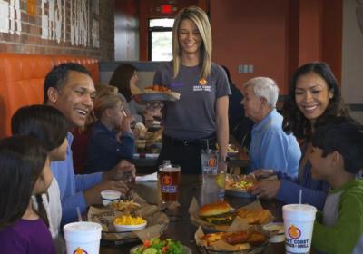 A server bringing food to a table of guests at East Coast Wings + Grill.