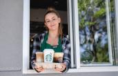 Starbucks employee holding Pumpkin Spice latte. 