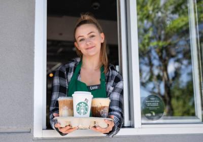 Starbucks employee holding Pumpkin Spice latte. 